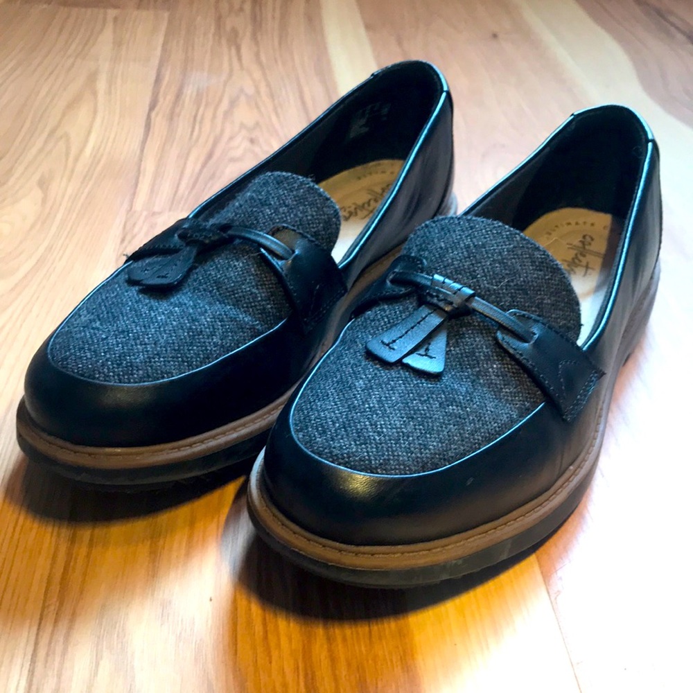 Black loafers with gray textured toe and tassel. Chunky sole, no heel.
